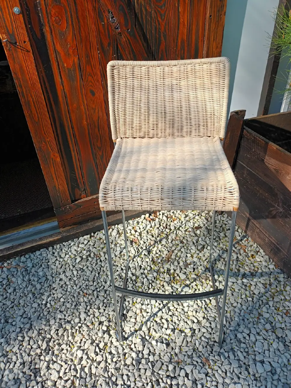 Moderner Barhocker mit silberfarbenem Metallgestell und hell geflochtener Sitzfläche und Rückenlehne.