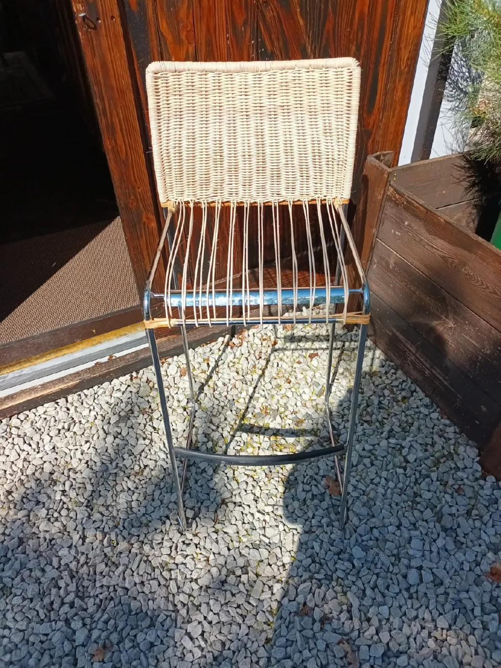 Barhocker mit Metallgestell und fertig geflochtener heller Rückenlehne. Die Sitzfläche befindet sich noch in der handwerklichen Neuflechtung.